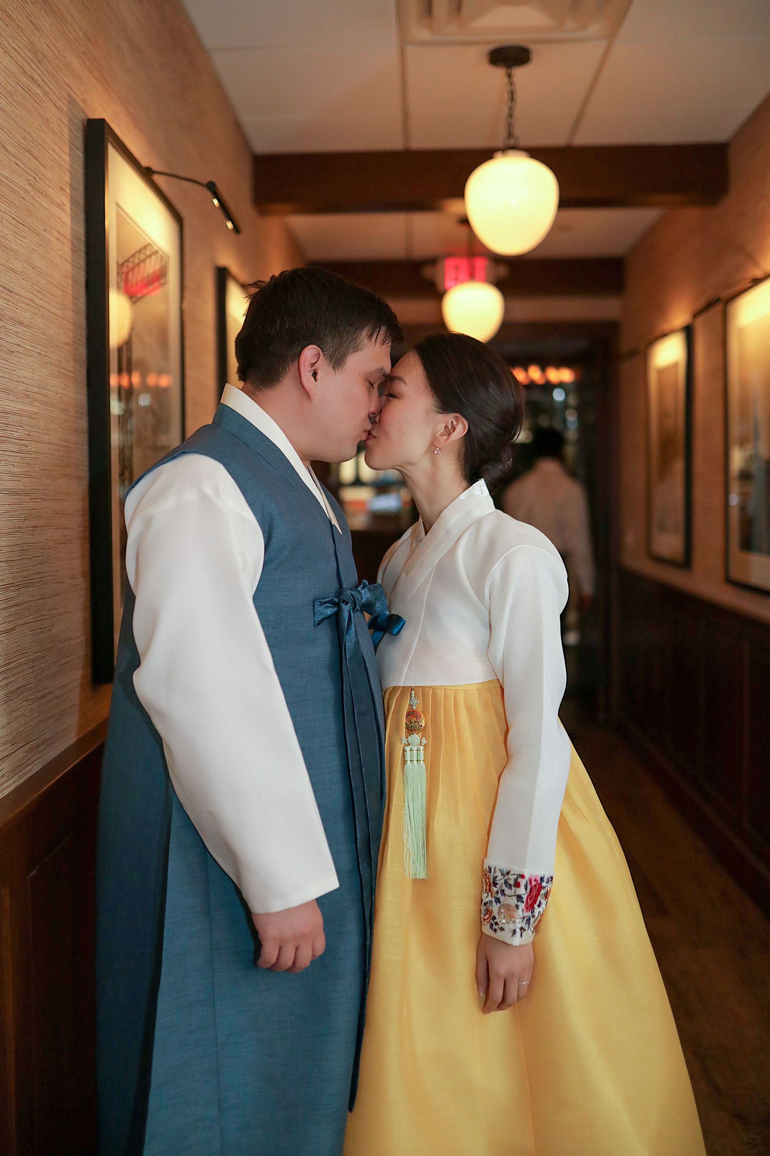 A romantic moment in a dimly lit hallway with soft lighting and vintage decor.