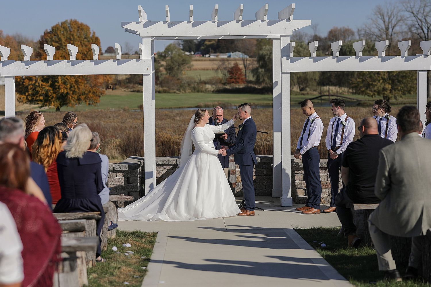 Outdoor wedding ceremony setup with white chairs and decorative elements against a natural landscape.