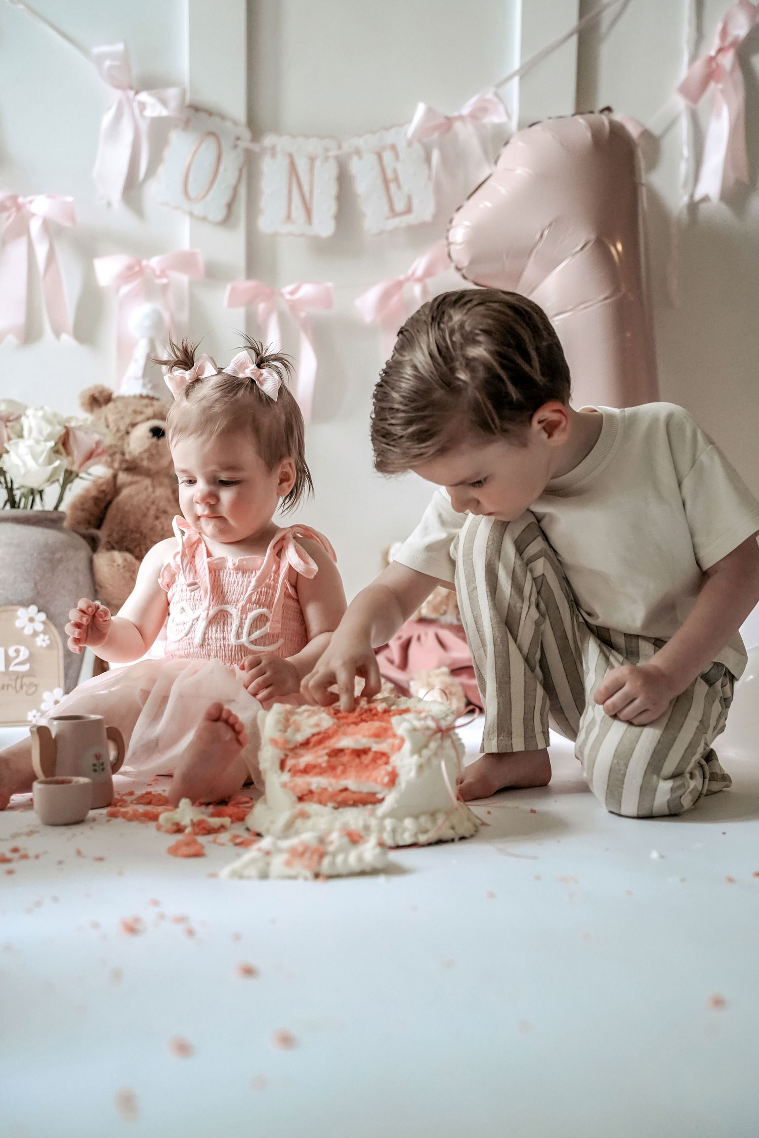 A series of four images showing a baby's first birthday cake smash photo session in soft pink tones.