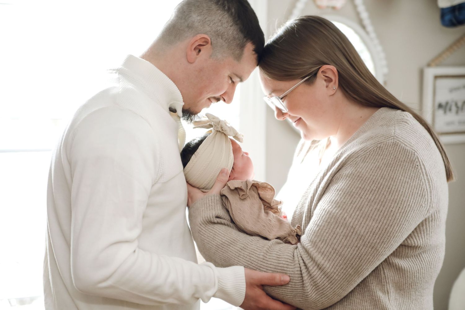Parents hold and gaze lovingly at their newborn baby in a series of tender moments at home.