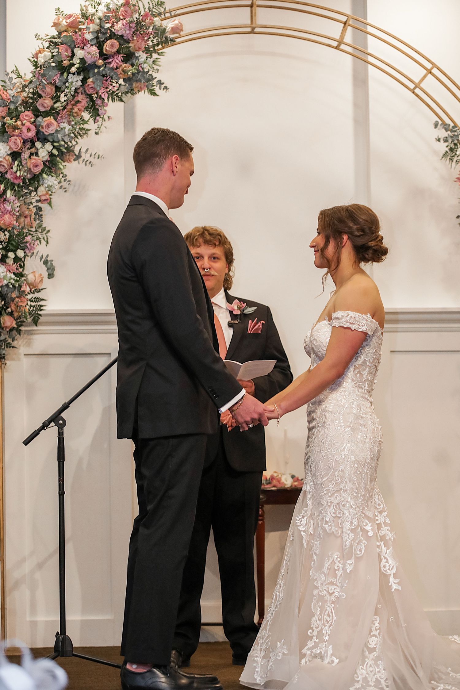 Wedding ceremony sequence showing couple exchanging vows under floral arch in elegant indoor venue.