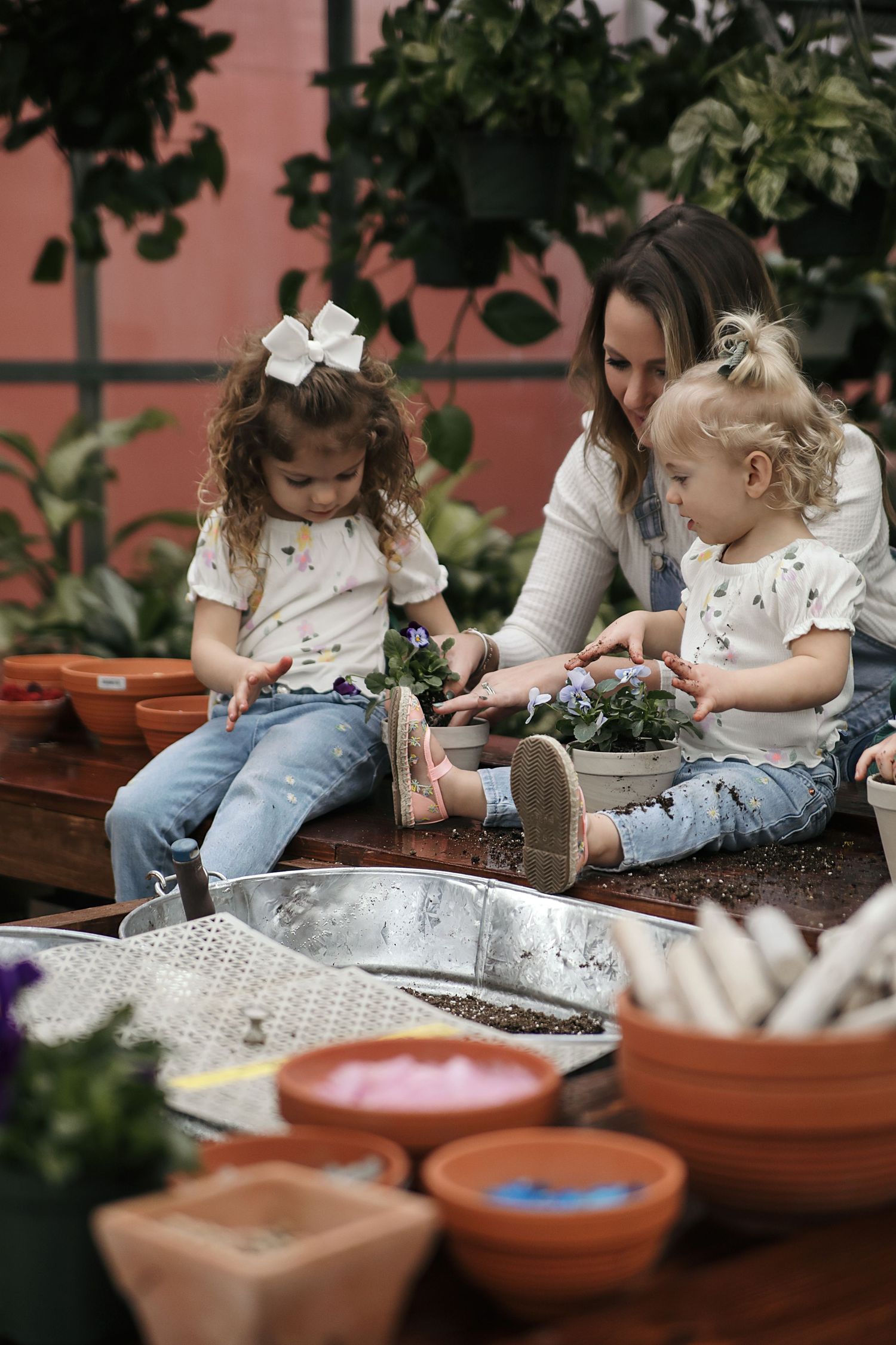 Young children planting seeds together in terracotta pots during a fun gardening activity.