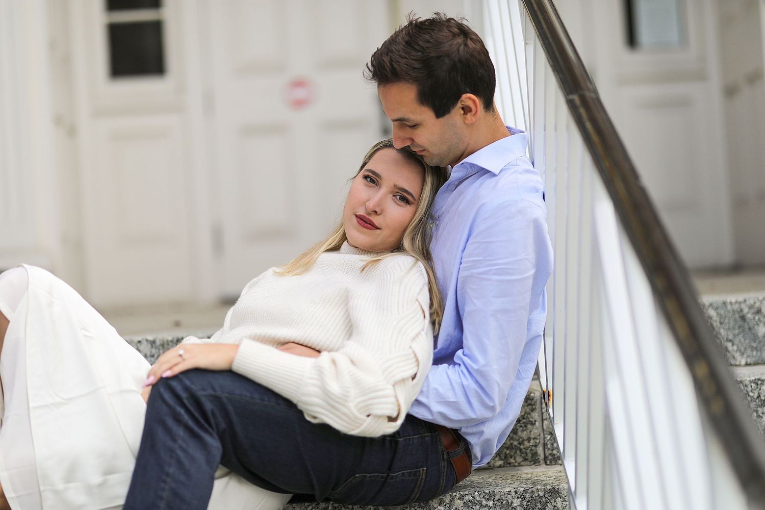 Couple relaxing together on concrete steps, wearing cozy sweaters on a peaceful afternoon.