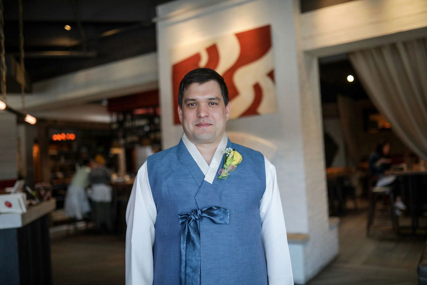 A person in a blue vest and white shirt stands in a retail or business setting.