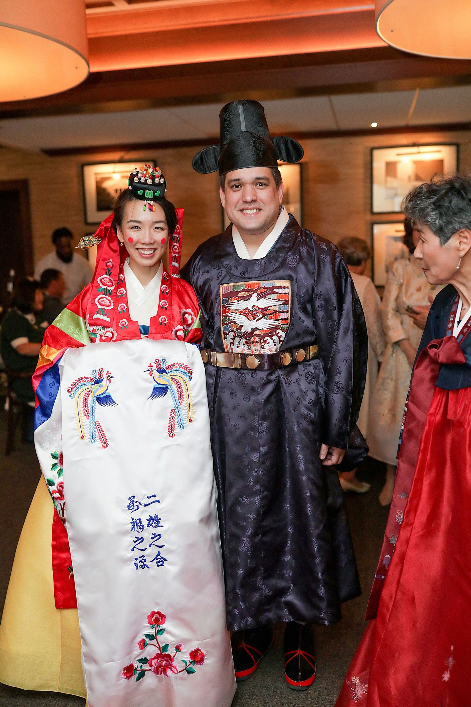 Traditional Korean wedding celebration with guests wearing colorful hanbok attire and ornate ceremonial clothing.