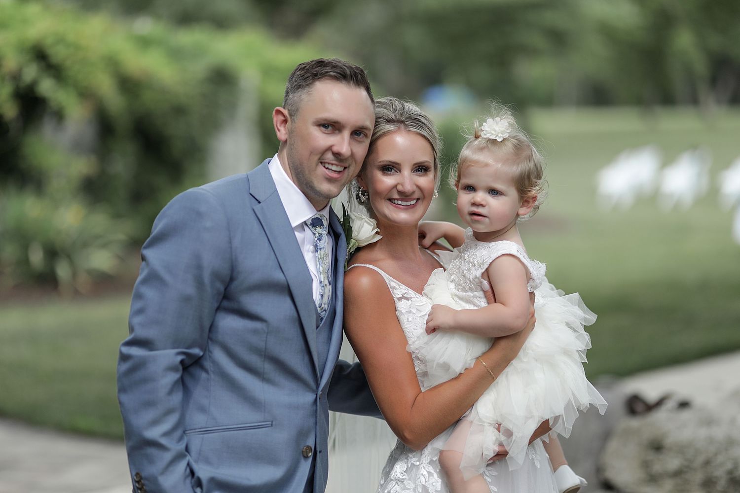 A sweet family wedding portrait outdoors with a small child in white.