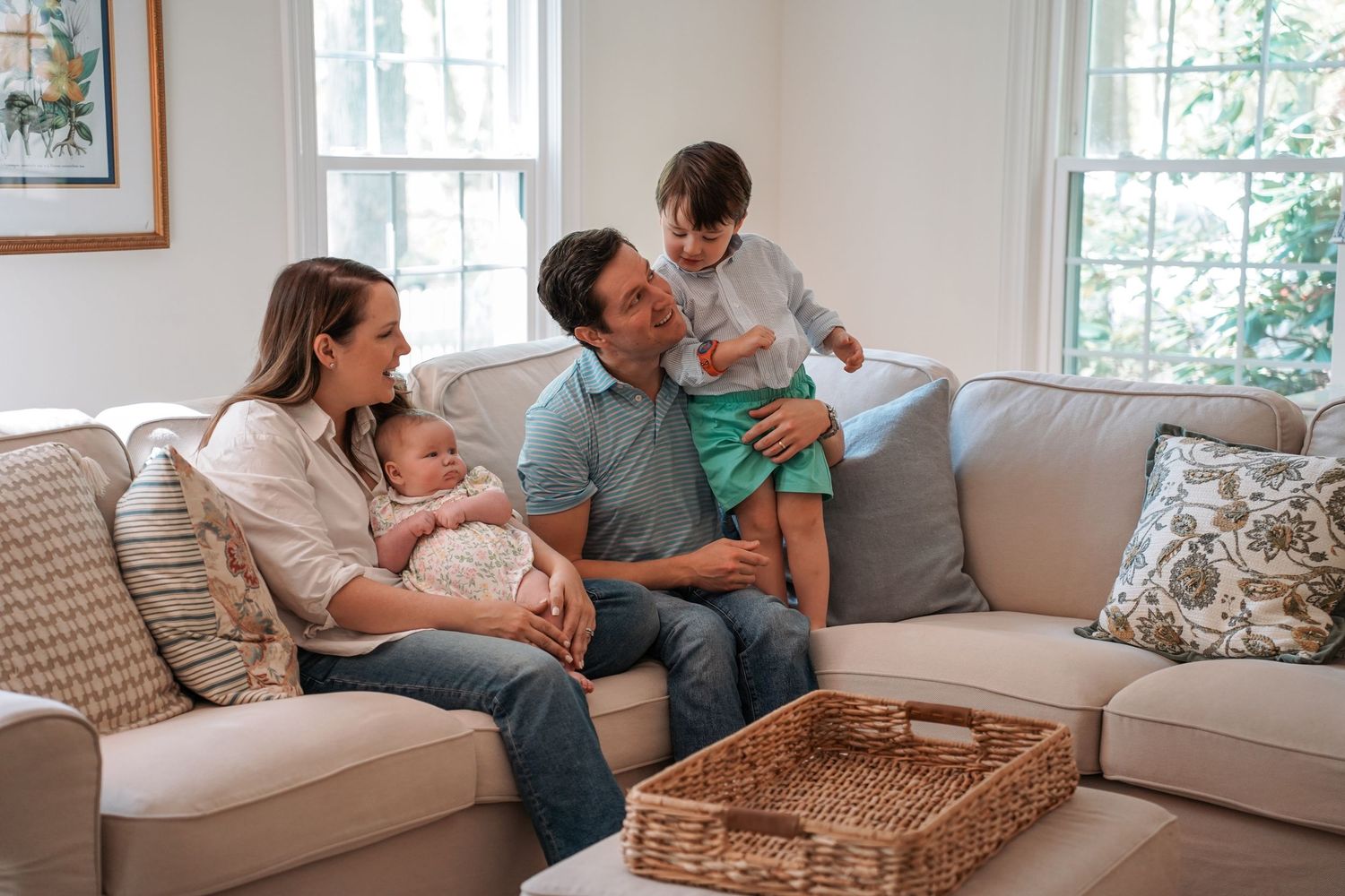 A cozy family moment on a beige sectional sofa with cushions and a woven basket in a bright living room.
