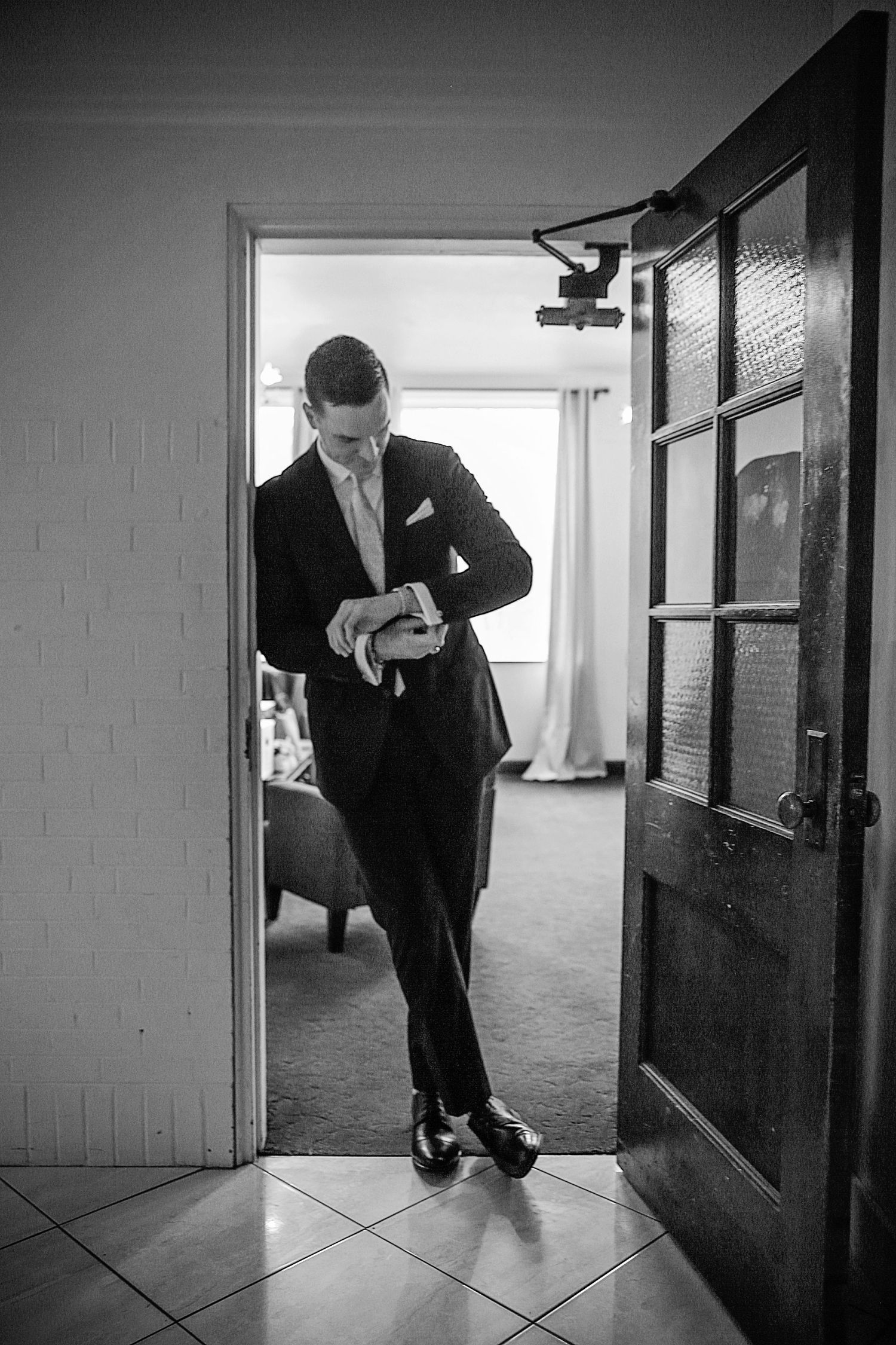 A sequence of black and white photos showing someone in a suit peering through doorways in an empty hallway.