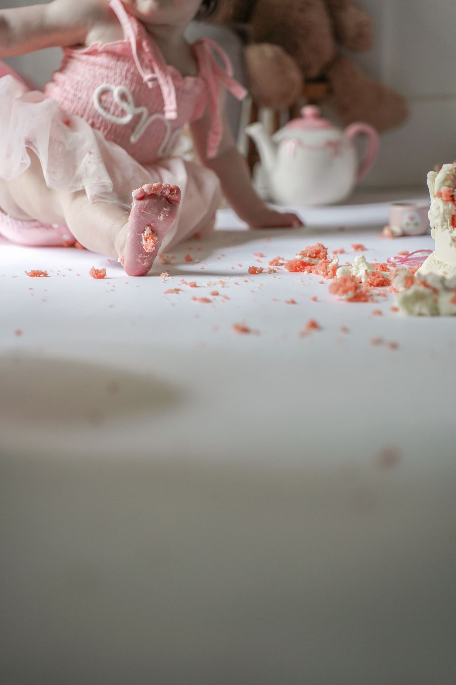 Elegant tea set arrangement in soft pink and white tones with scattered confetti on a light surface.