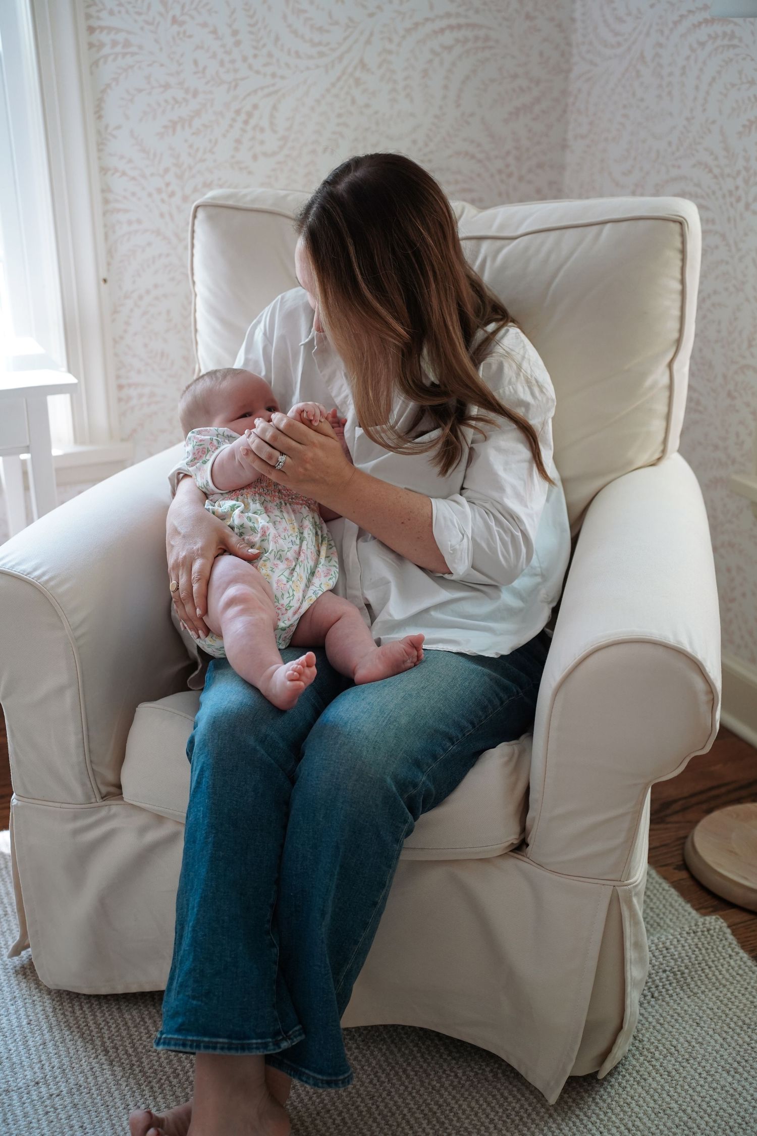 Four sequential images showing a breastfeeding scene on a white armchair in a sunlit room with patterned wallpaper.