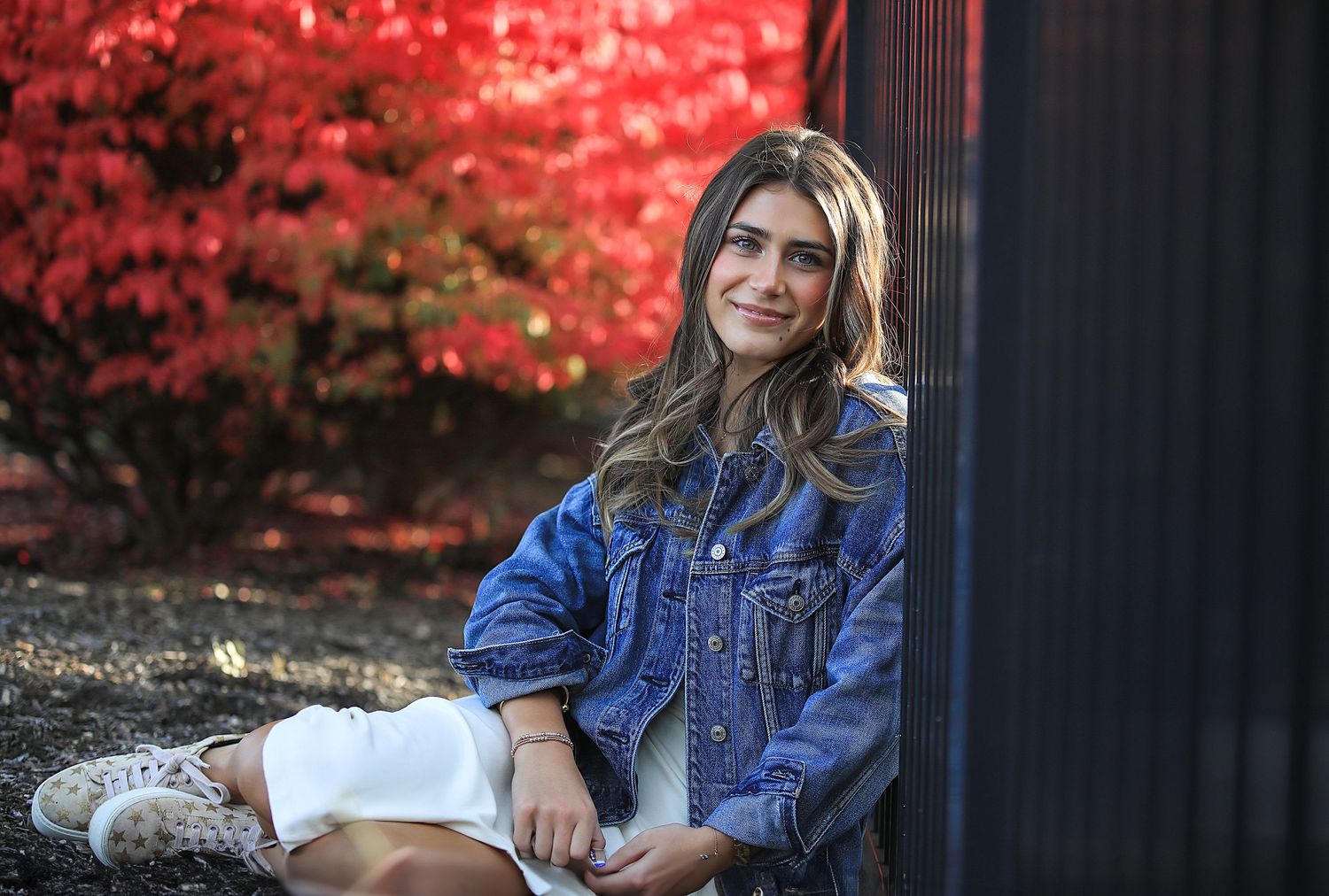 Senior Photography Chagrin Falls Ohio. A casual autumn portrait featuring blue denim jacket against vibrant red fall foliage background.
