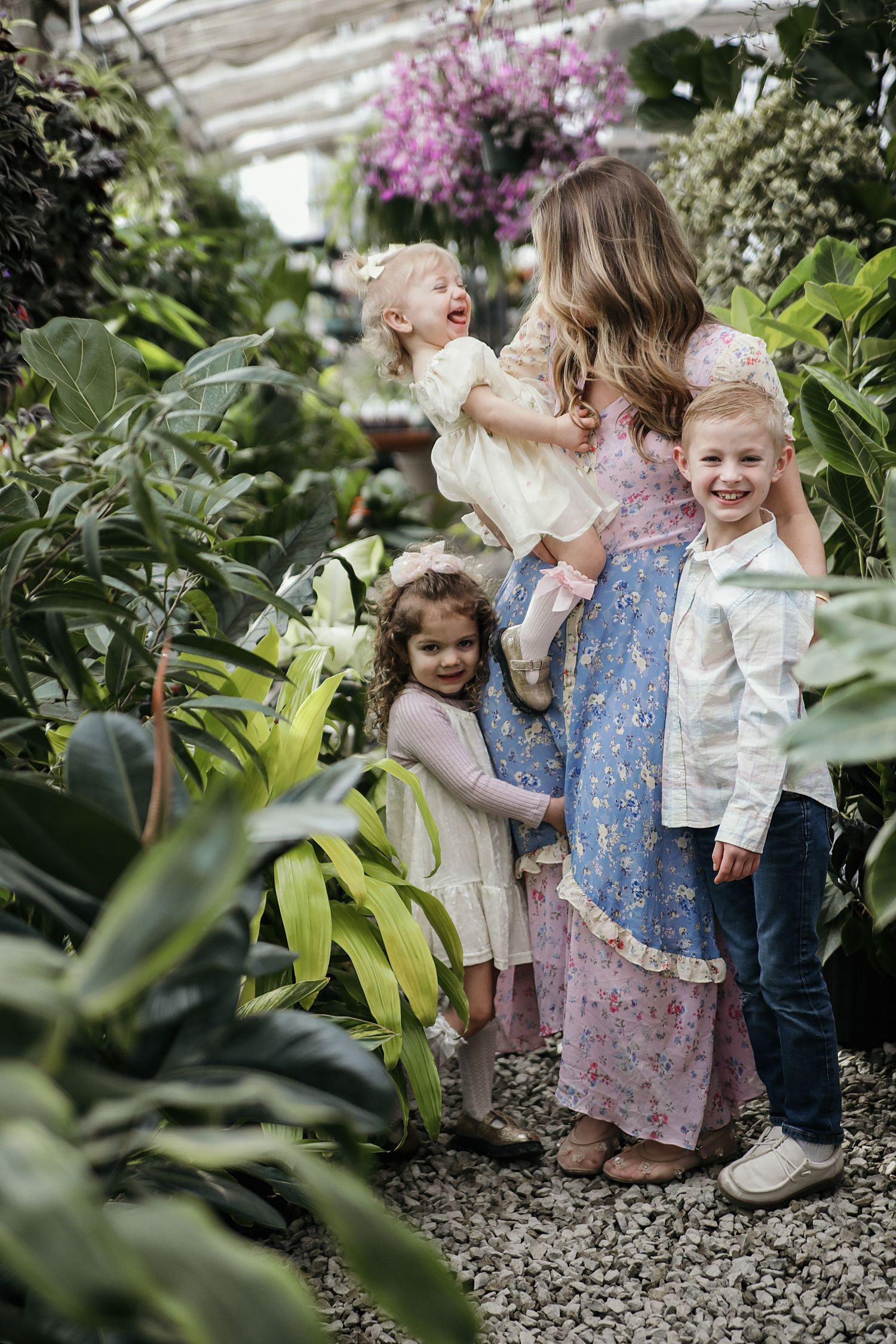 Young children playing and having fun together in a lush botanical garden greenhouse setting.
