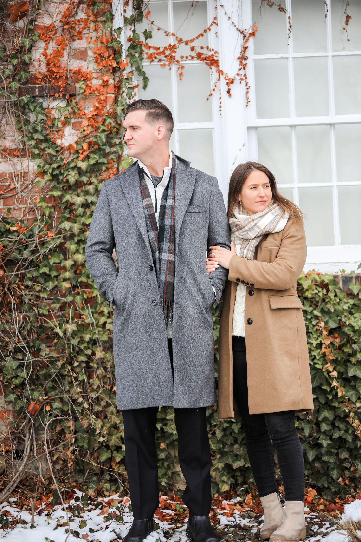 A couple in winter attire stands against a white wall with orange ivy, sharing intimate moments in four connected photos.