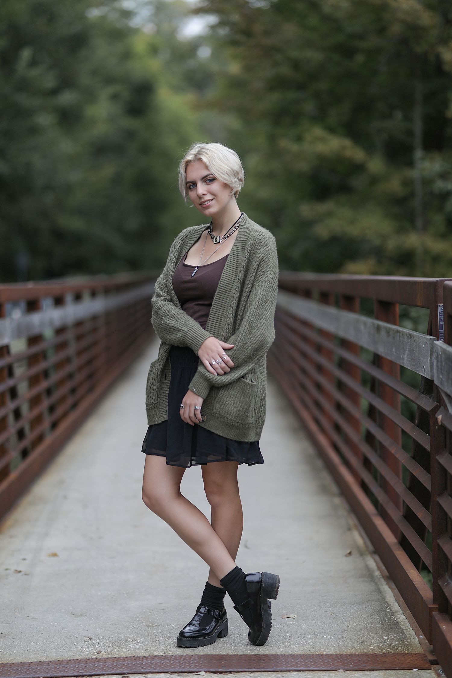 Four outdoor fashion shots showcase a stylish outfit and boots on a wooden bridge walkway surrounded by greenery.