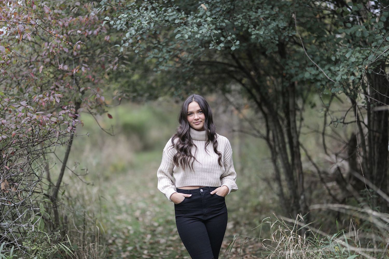 A rustic outdoor photoshoot in a wooded area with tall grass and natural greenery.