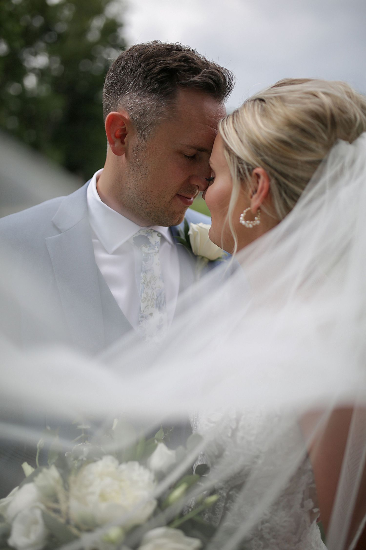 A romantic moment shared between newlyweds under a flowing white veil.
