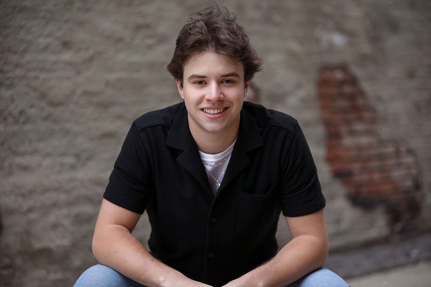 A series of casual portrait photos showing someone in a black shirt against a textured brick wall background.
