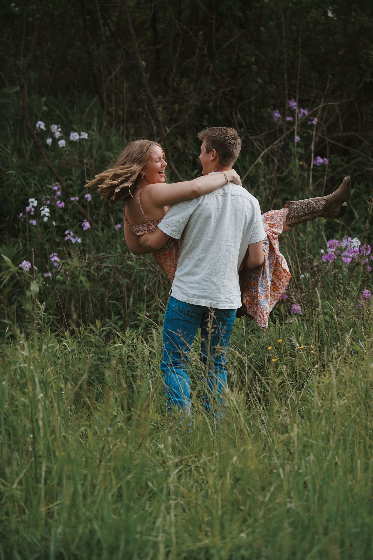 A romantic moment captured in a wildflower meadow with tall grass and purple blooms in the background at dusk.