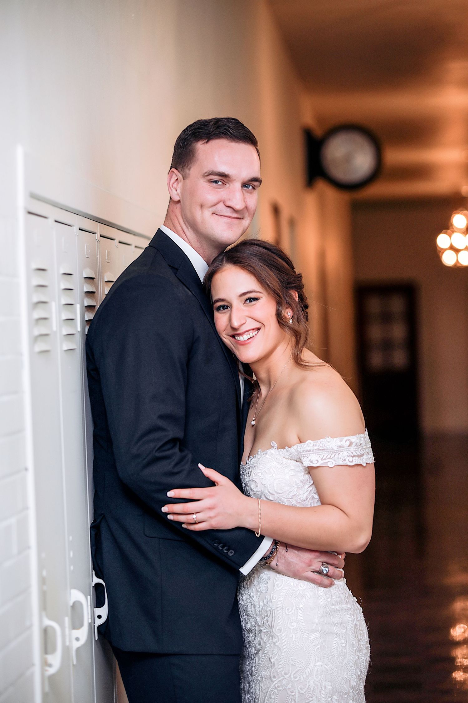 A couple shares intimate wedding moments against a warm indoor backdrop with white columns and elegant lighting.