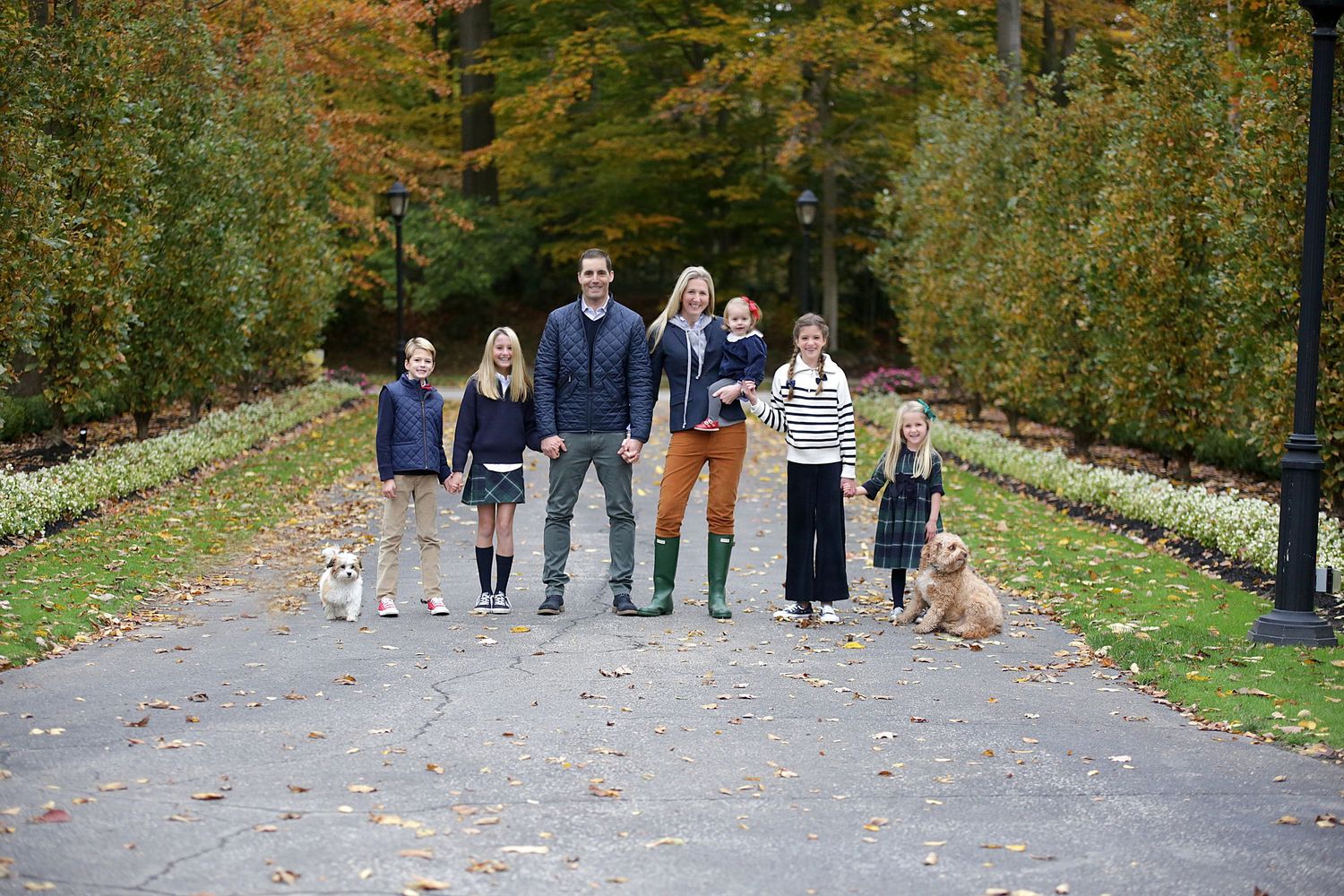 Family with children and dog walking together on tree-lined autumn path.  Family Photography in Chagrin Falls Ohio