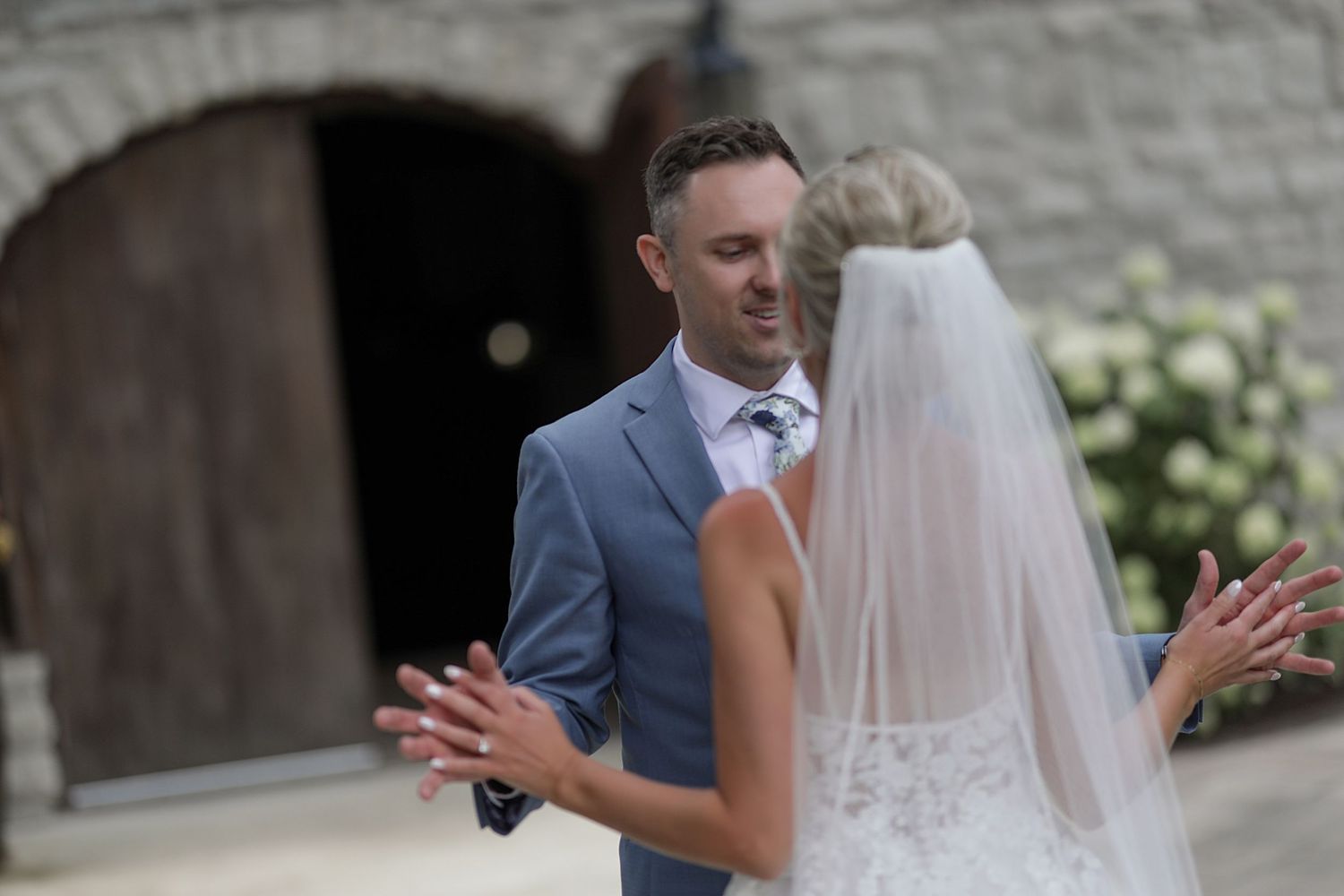 Wedding couple shares first look moment outside stone building.
