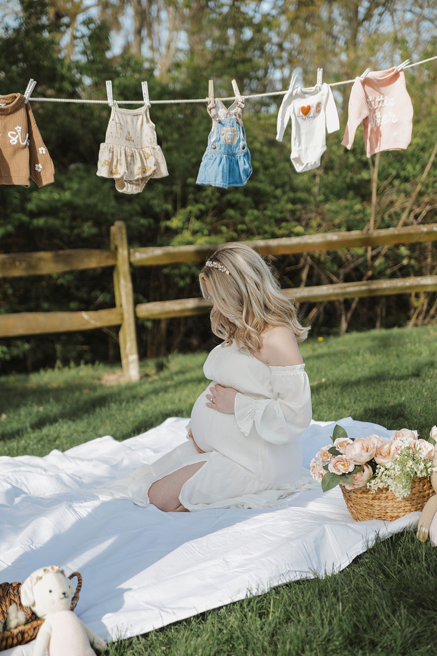 Vintage style laundry line with clothes drying above a white blanket on grass in a sunny garden setting.