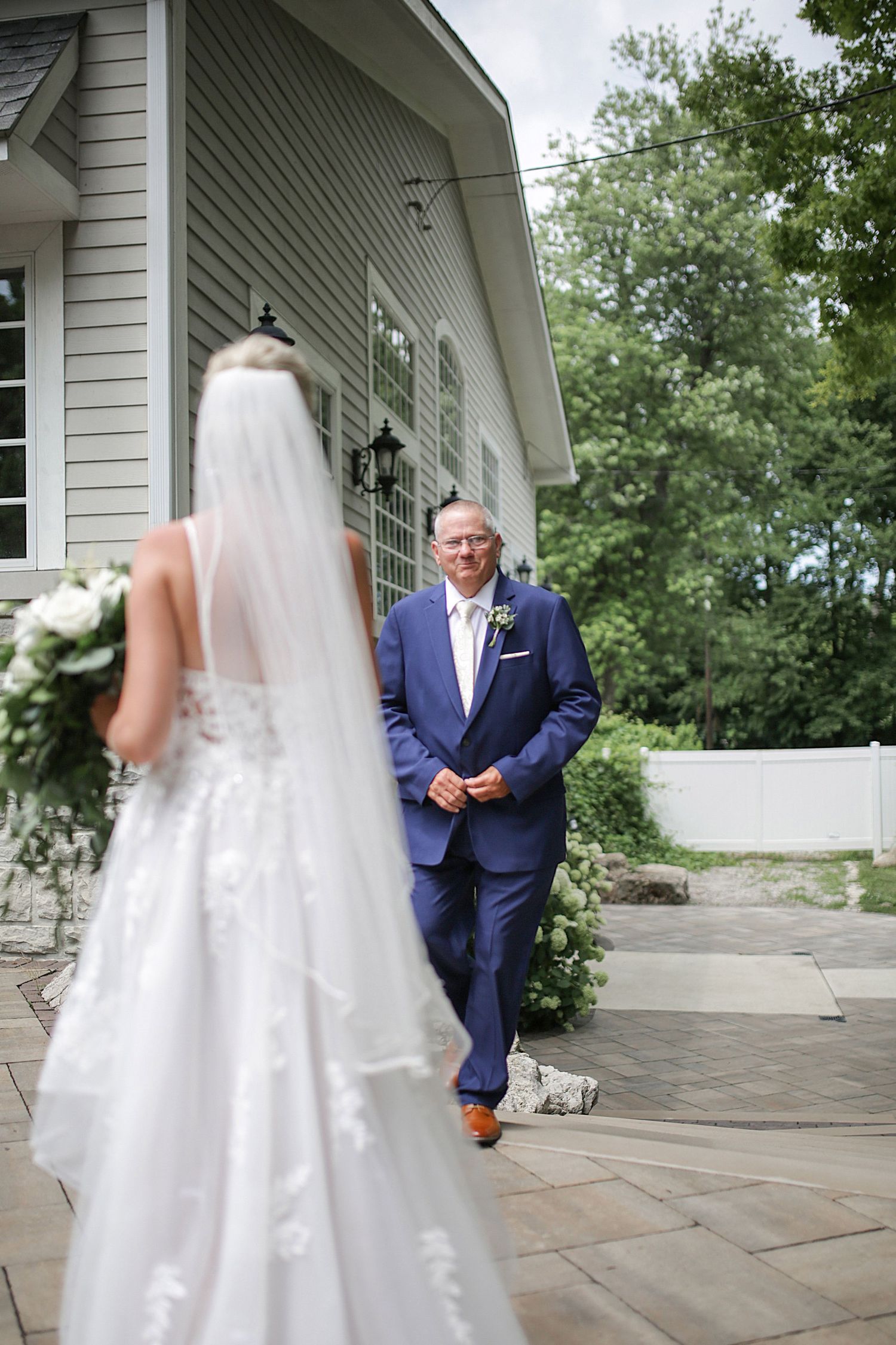 First look moment outside white colonial style building with stone patio.