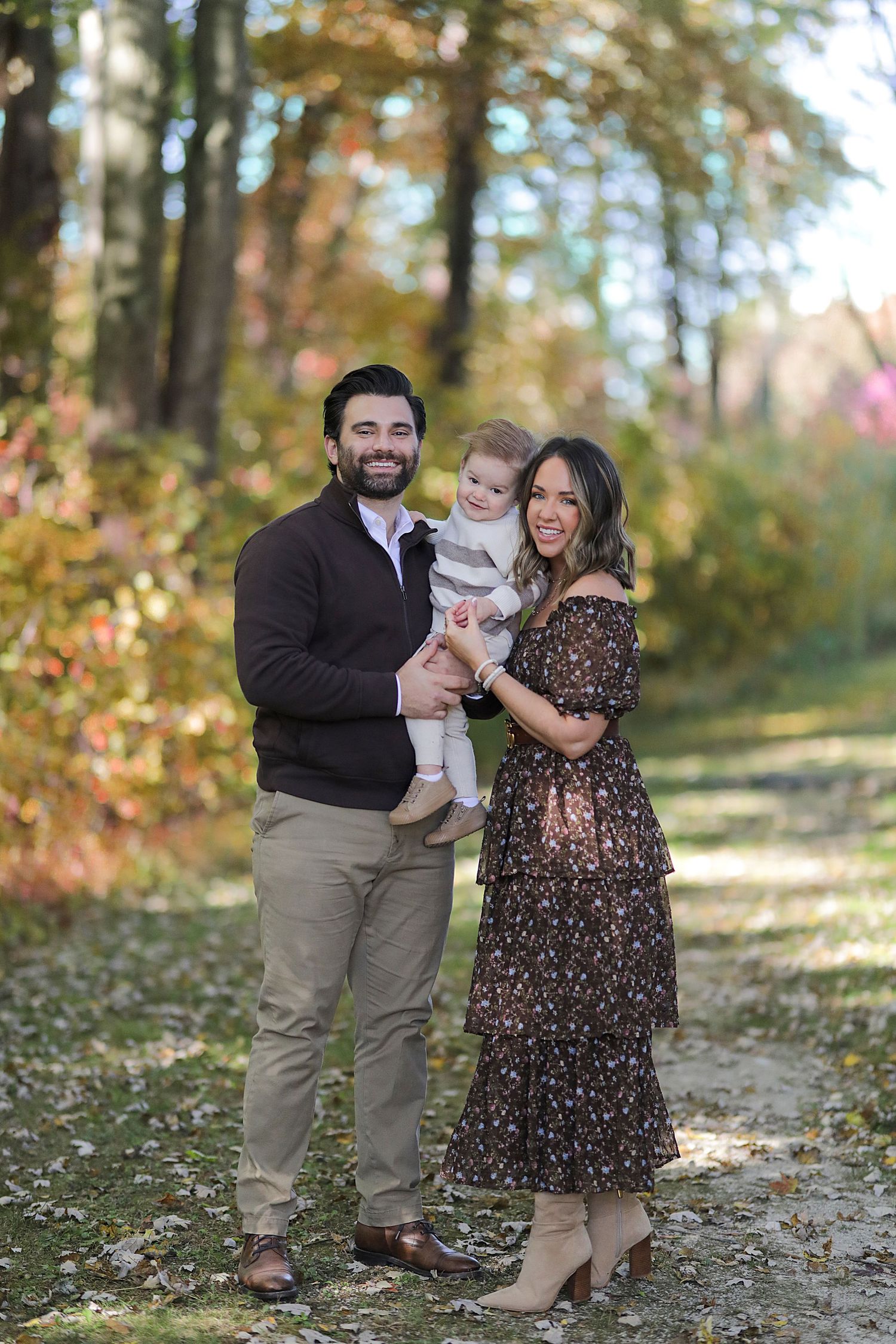 A family stands together on an autumn path surrounded by golden fall foliage.  Family Photography in Medina Ohio.