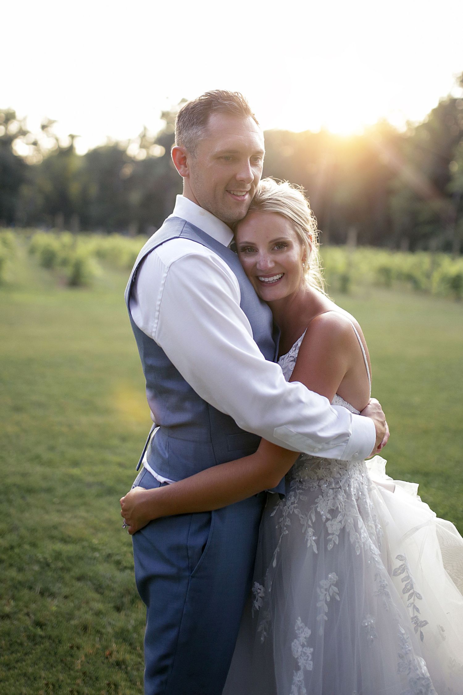 Romantic sunset portraits of newlyweds embracing in a grassy field.