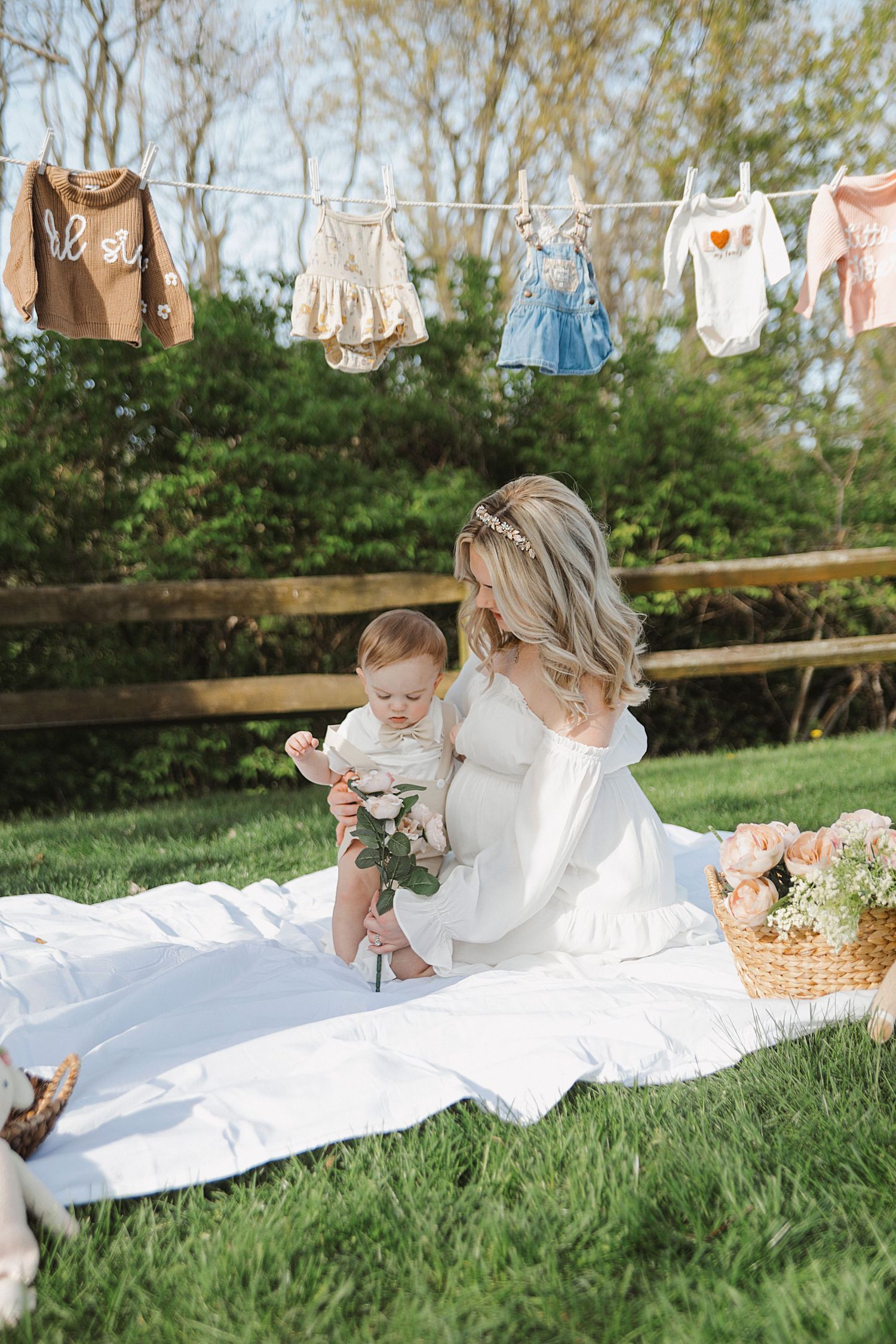 Picnic scene on grass with white blanket and vintage bunting decorations. Maternity photographer Medina Ohio.