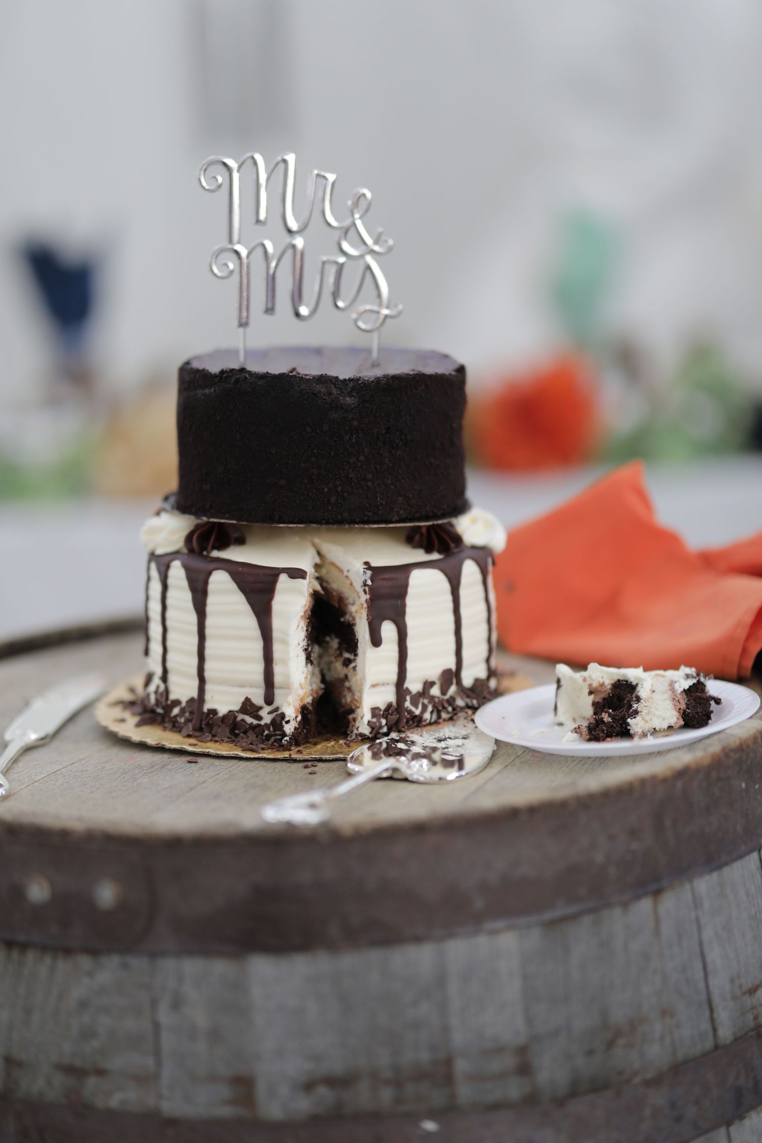 A two-tiered black and white wedding cake with dripping chocolate and a 'Mr & Mrs' cake topper.