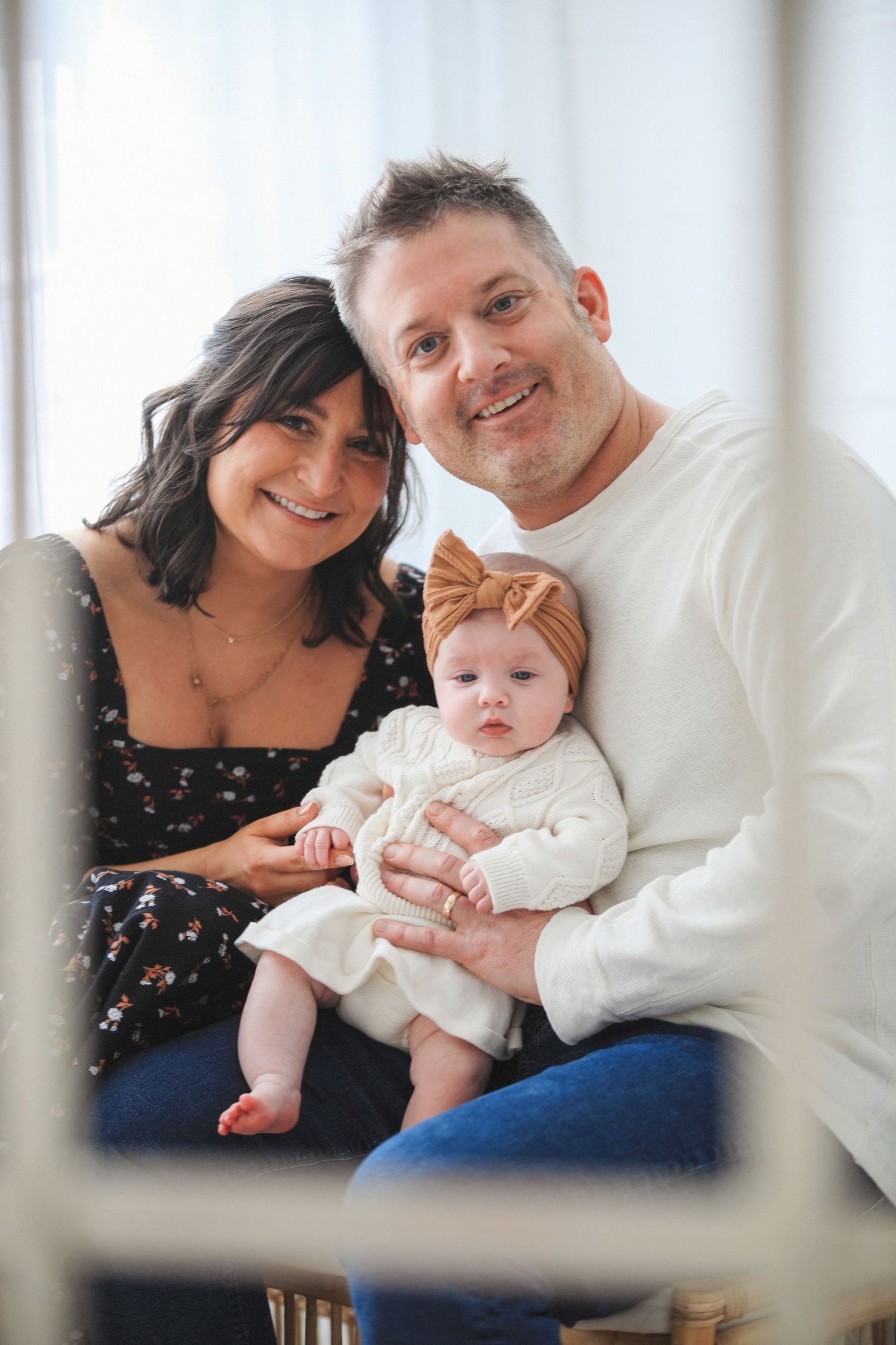 Family poses together on couch in matching white and navy outfits for holiday portraits.