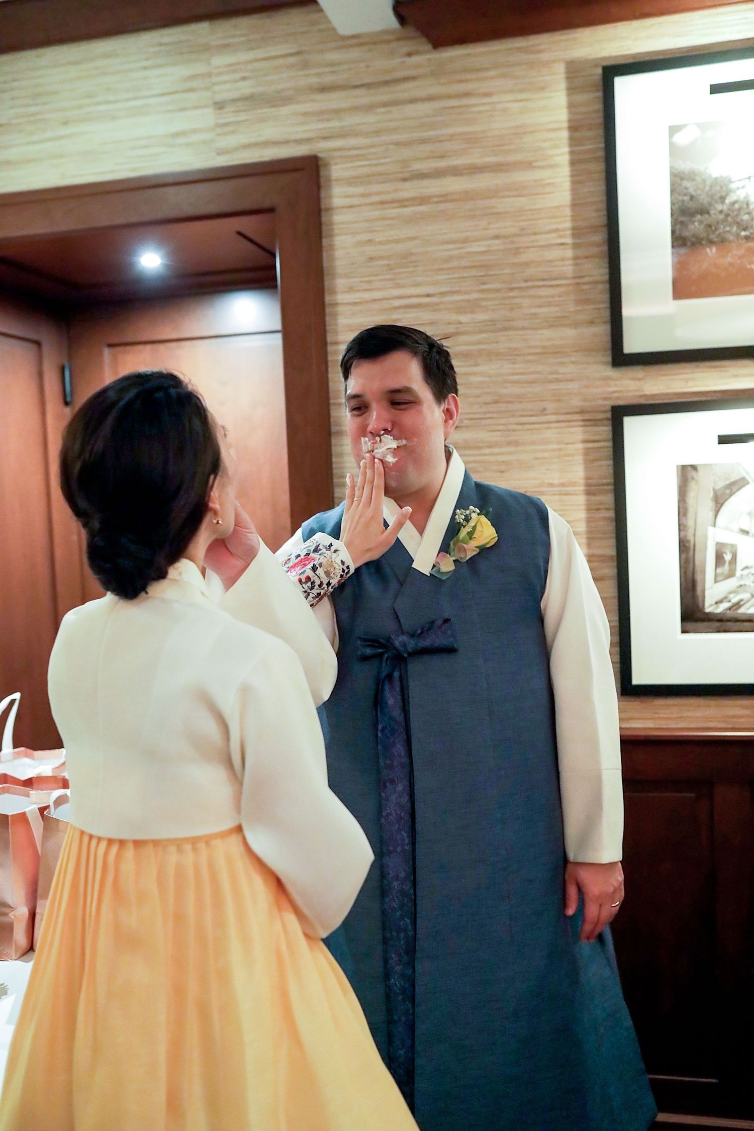 A couple in traditional Korean hanbok attire share an intimate moment during their wedding celebration.