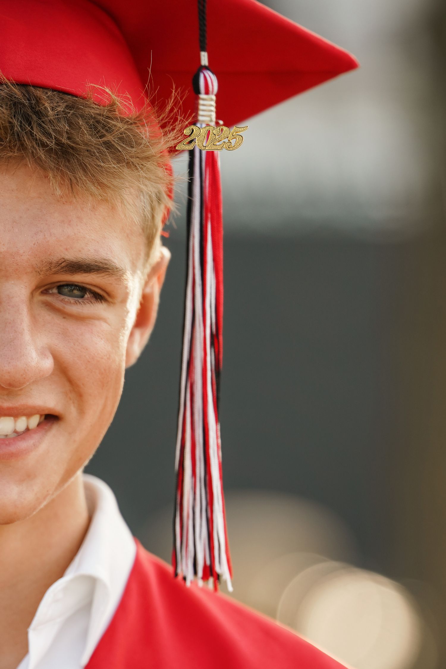 A graduate wearing a bright red cap and gown with a white tassel on graduation day.
