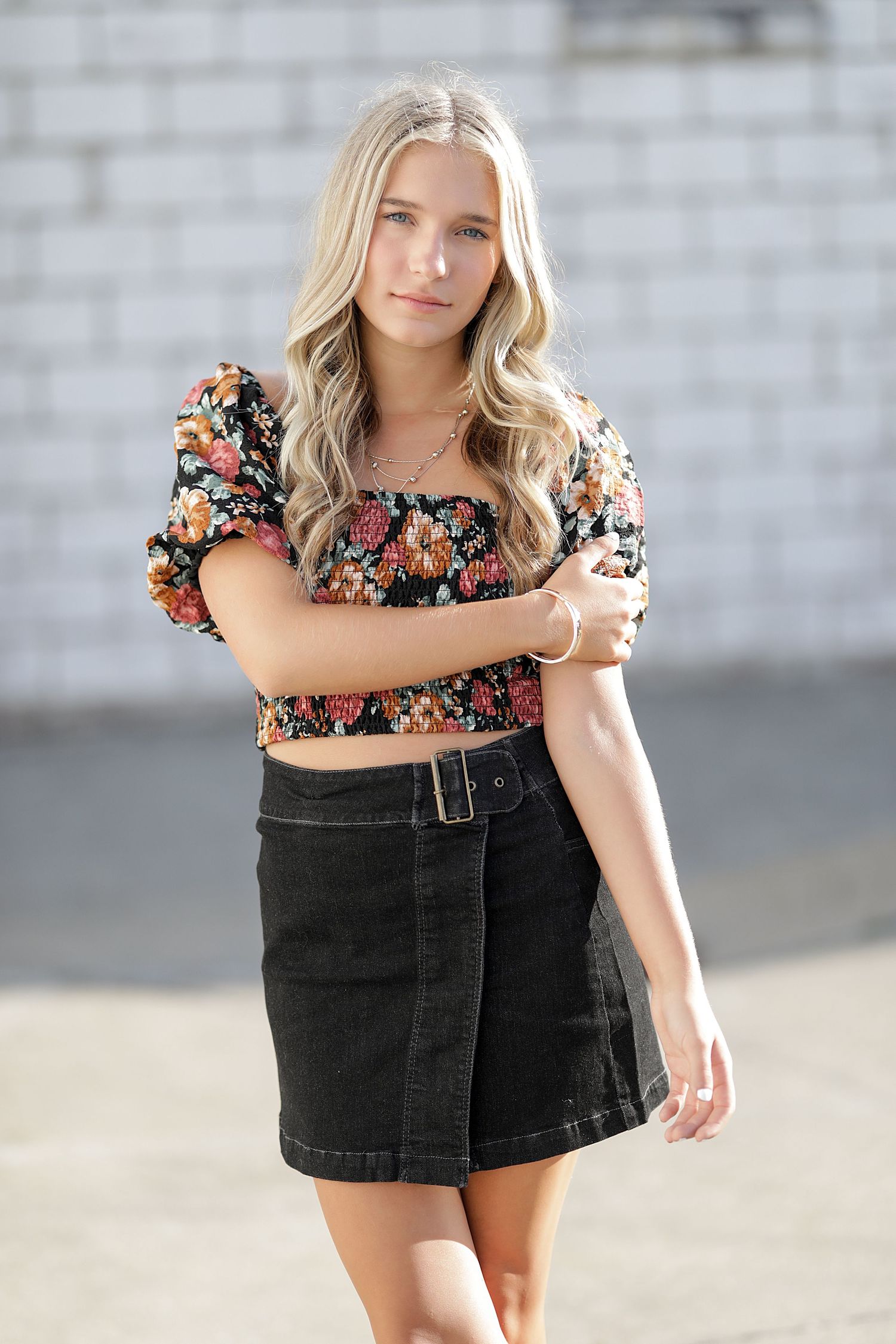 Fashionable outfit featuring a floral crop top paired with a black denim mini skirt in outdoor setting.