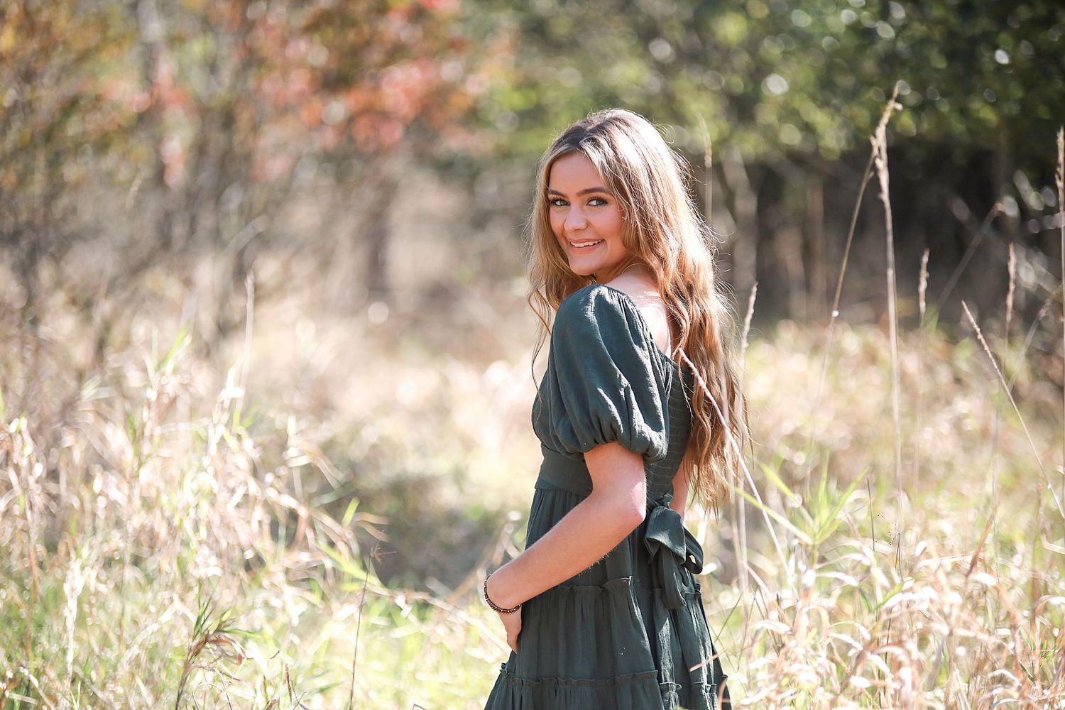 Senior Photography Medina Ohio. Outdoor portrait in a field wearing a dark green dress with sunlit natural backdrop..
