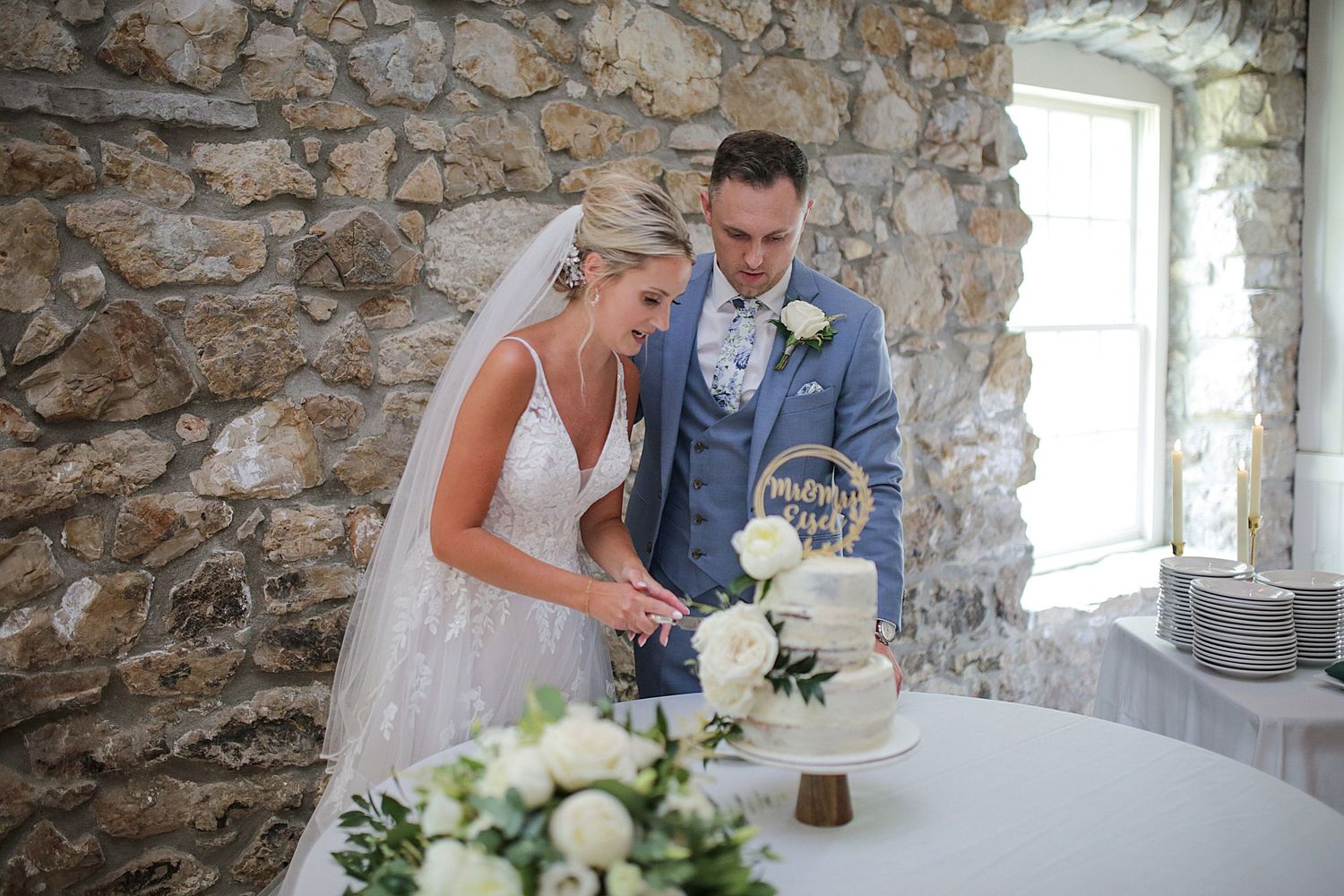 Wedding celebration at rustic stone venue with table settings and floral decor.