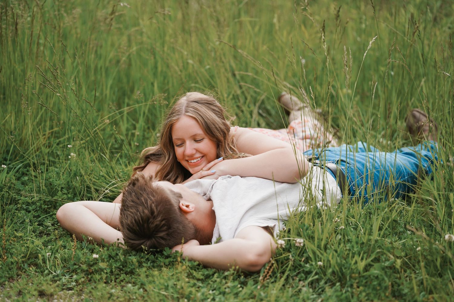Person lying in green grass field enjoying a peaceful moment in nature with warm sunlight.