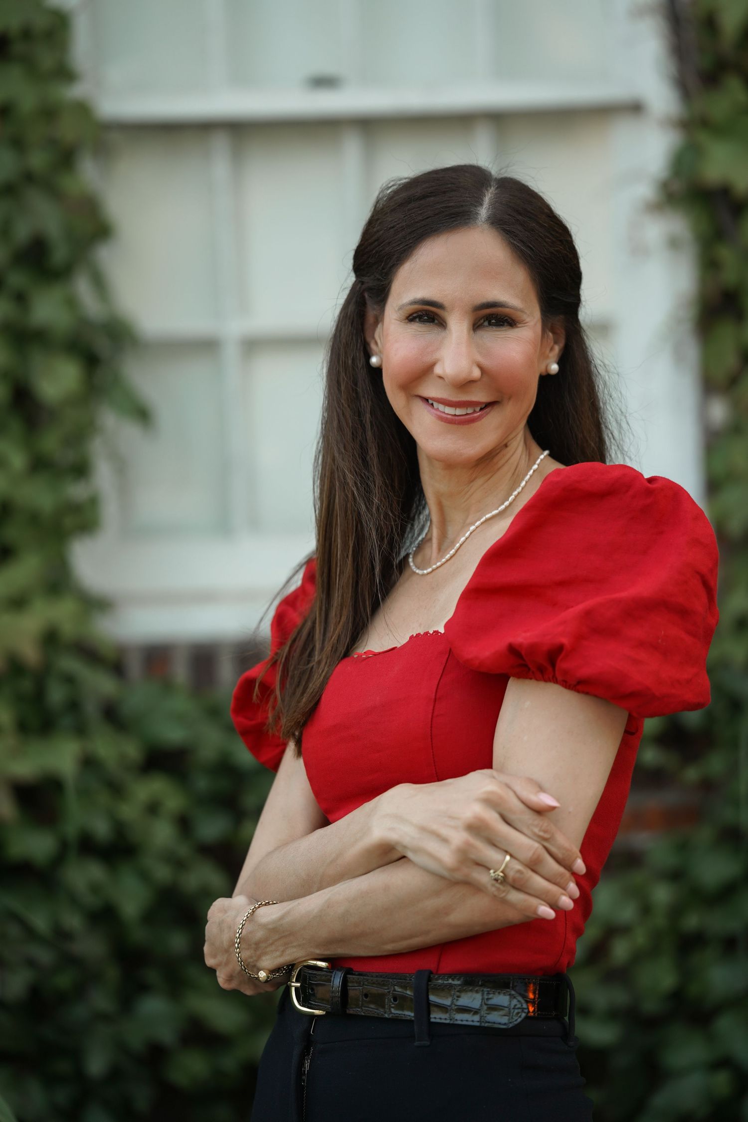 A sequence of poses showing someone wearing a vibrant red blouse against a garden background with ivy-covered walls.