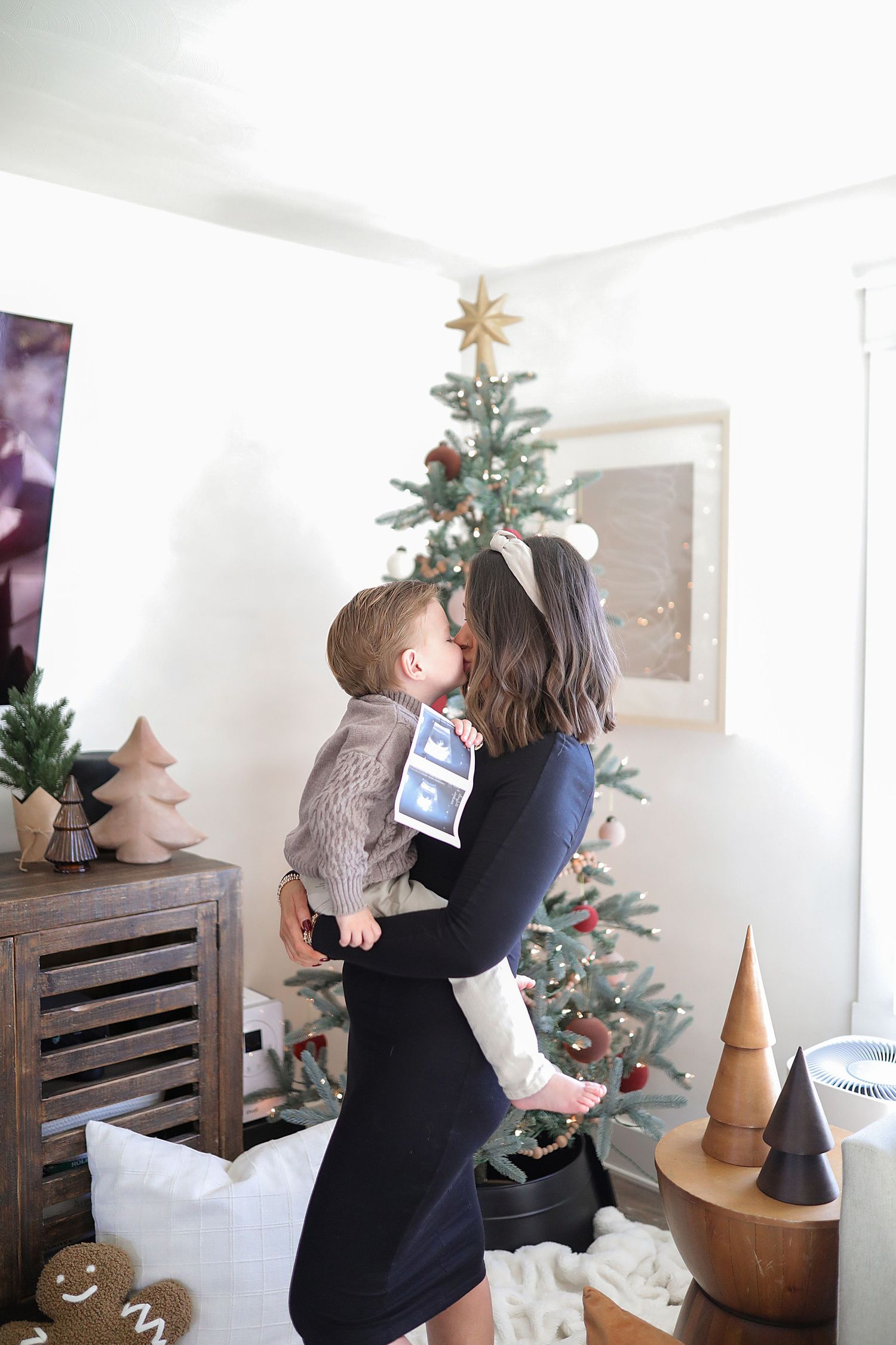 A series of four photos showing someone decorating a small Christmas tree with a gold star topper in a white room.