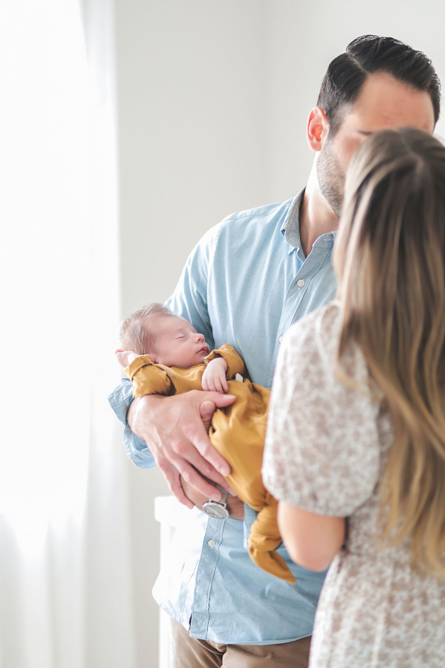 Family shares tender moment with newborn baby in bright indoor setting. Newborn photographer Brecksville, Ohio.