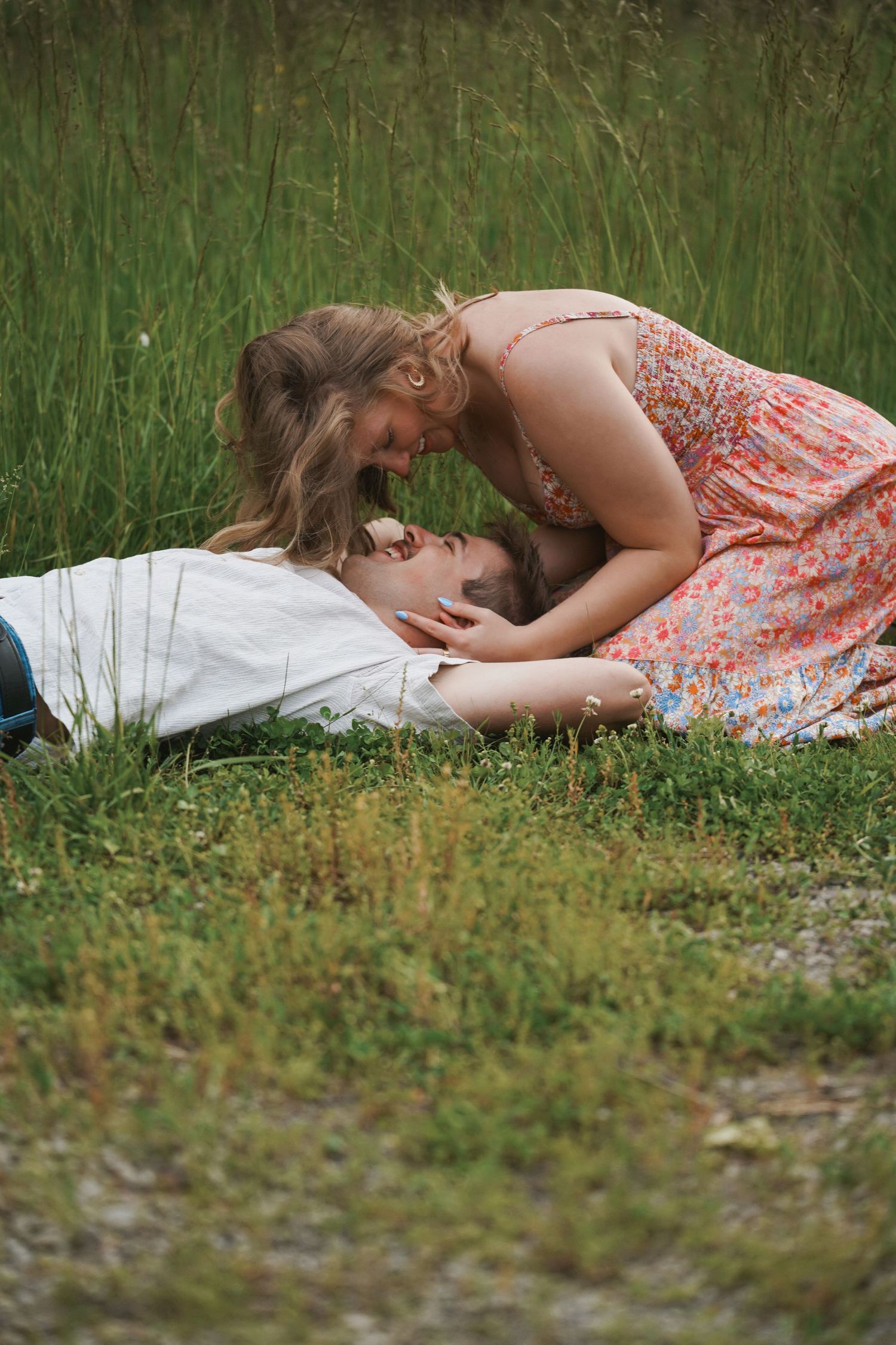 A romantic moment between two people lying in tall grass on a summer day.