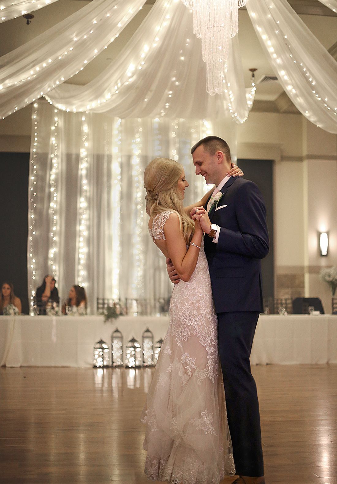 Couple shares their first dance under elegant white lights and chandeliers at wedding reception. Wedding Photographer in Cleveland Ohio