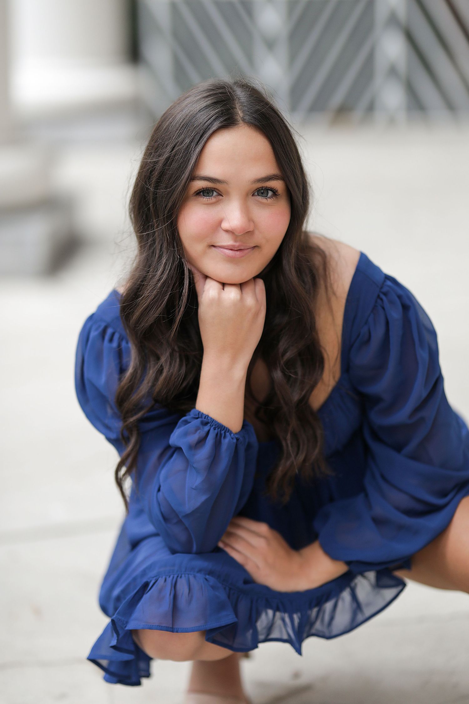 A person in a flowing royal blue dress poses playfully in different positions against a light background.