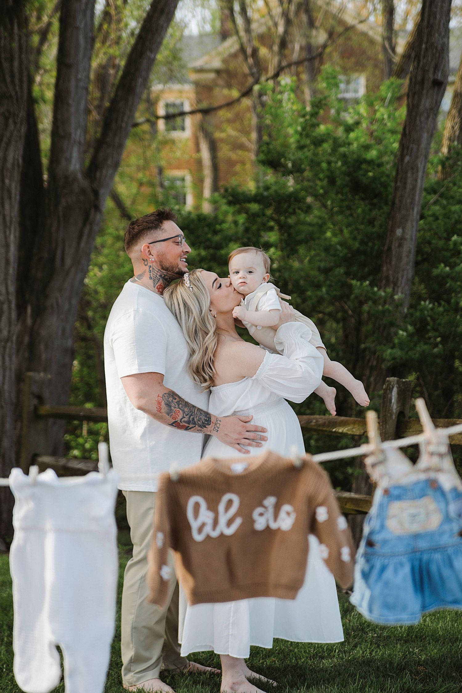 Family in white attire standing near clothesline in outdoor garden setting during photo session.