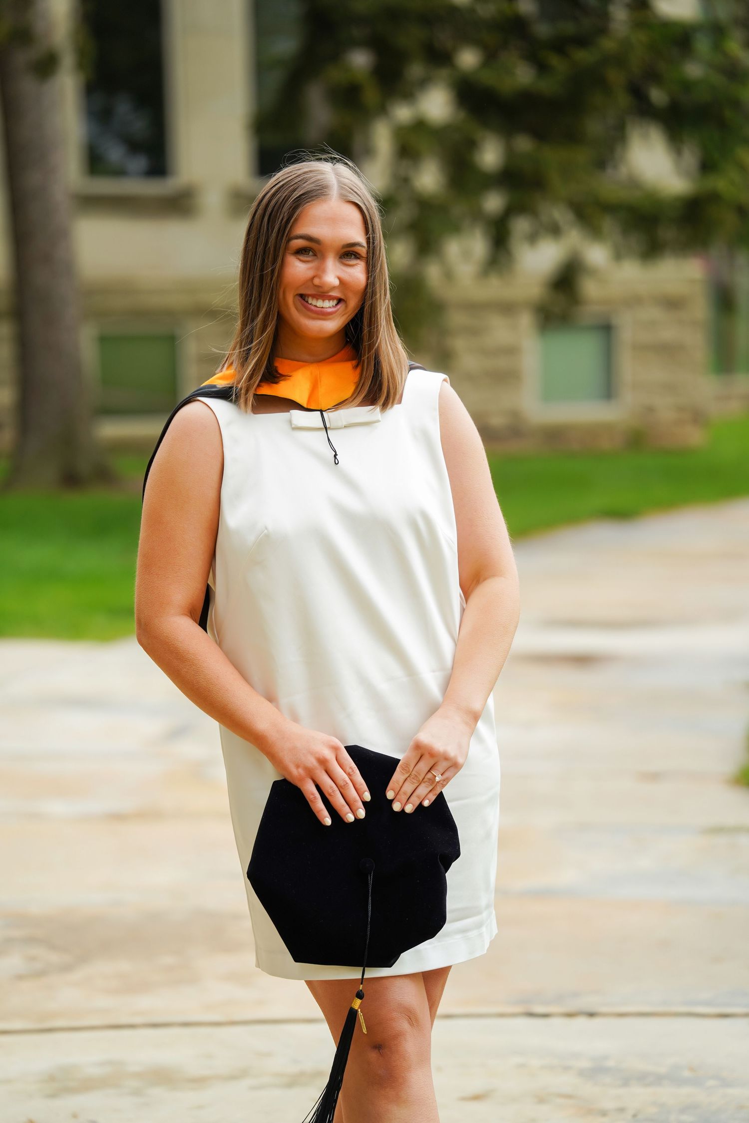 Person in casual black and white outfit smiling during an outdoor photoshoot on a sunny day.