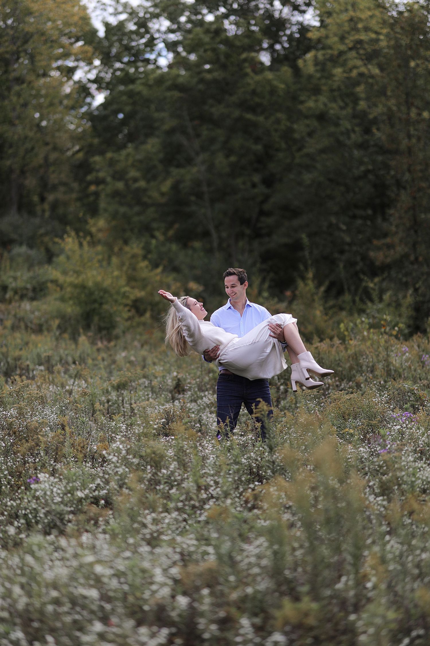 A couple dancing gracefully in a wildflower meadow surrounded by white flowers and greenery.