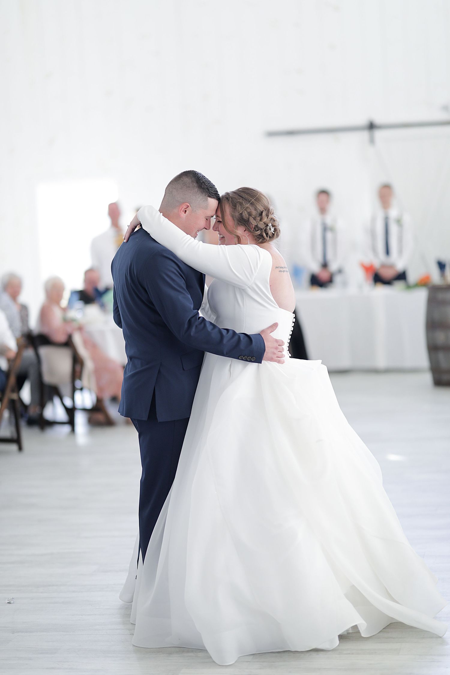 Couple sharing first dance in elegant white reception venue.