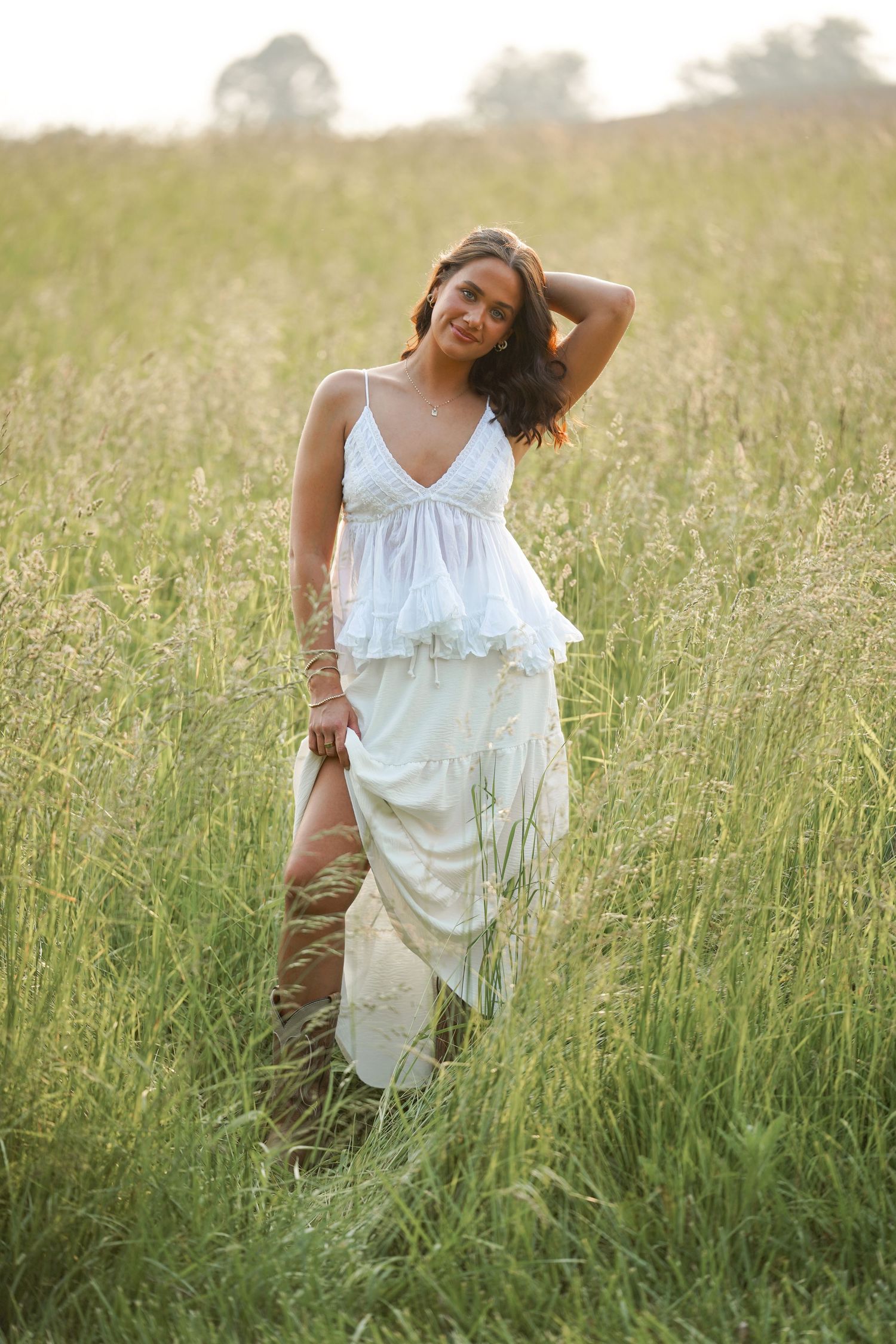 Artistic outdoor photography showing a person in white moving through tall grass during golden hour lighting.