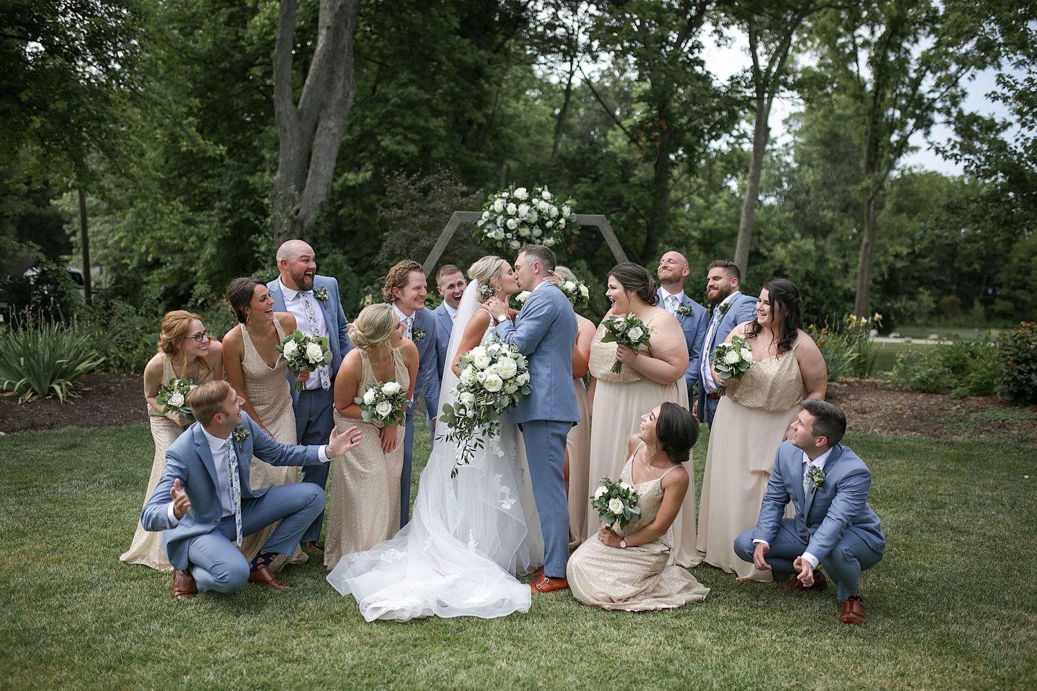 Wedding party relaxing on grass during outdoor photo session.